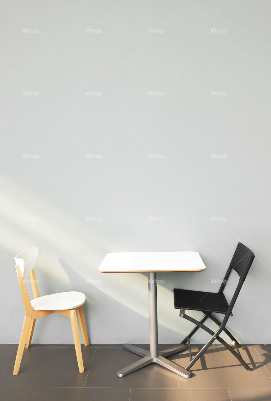Table and chairs in front of light gray wall