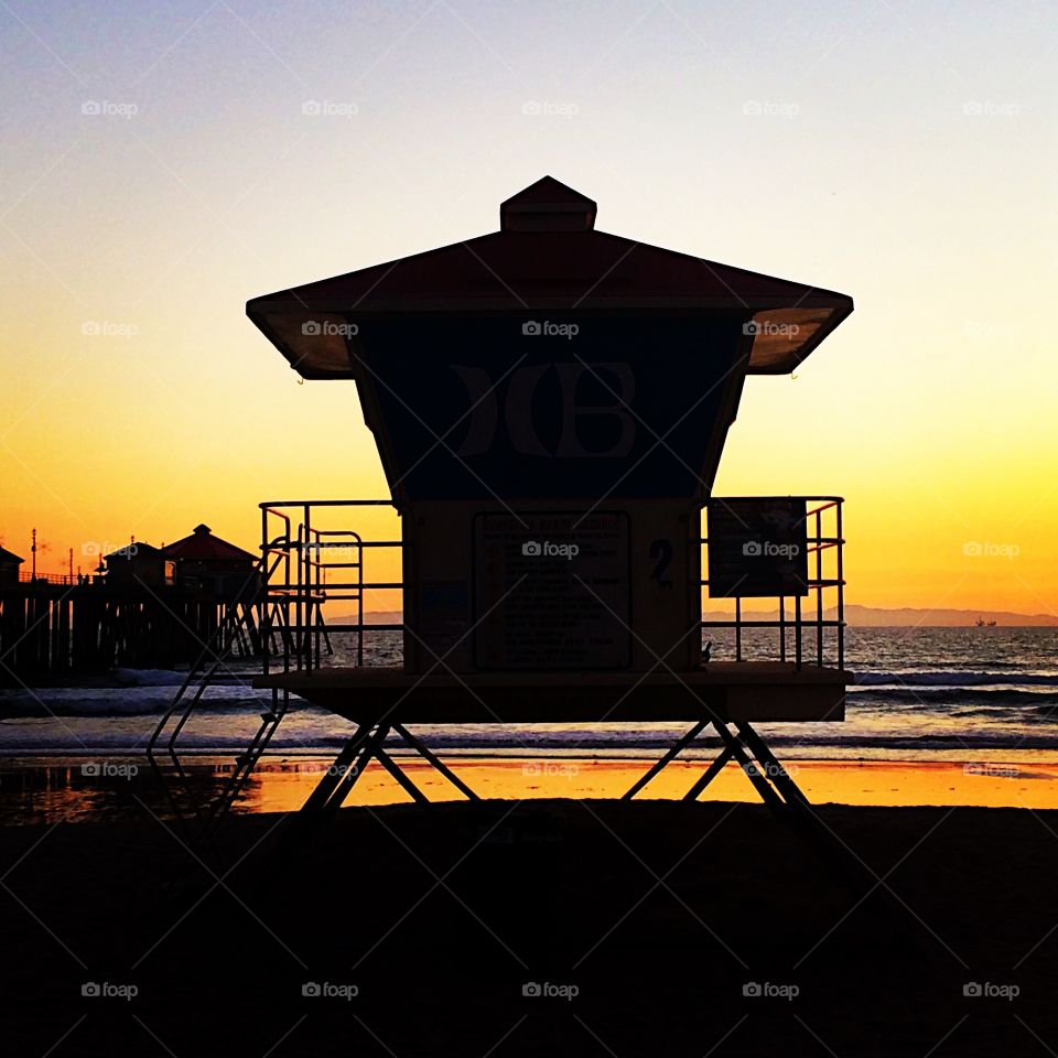Silhouette of lifeguard tower and pier at beach