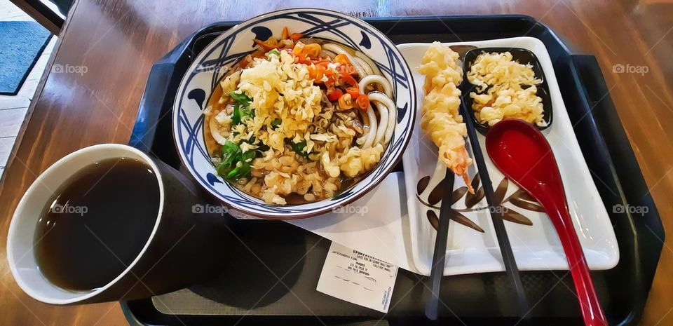 a bowl of noodles and glass of lemon tea, noodles topped with sliced spring onions, sliced cayenne pepper, fried powder, additional food for fried shrimp wrap, and fried flour powder, one red spoon, and a pair of shopsticks, good dishes, special nood