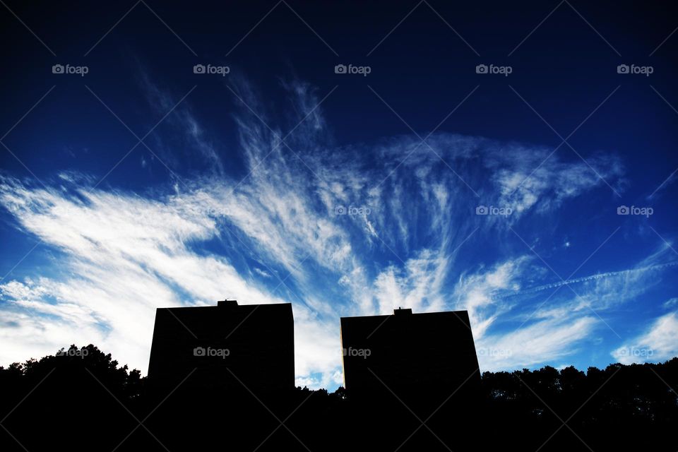 Cirrus clouds fill the cobalt blue skies above the silhouette of highrise apartment buildings in Weehawken, NJ.