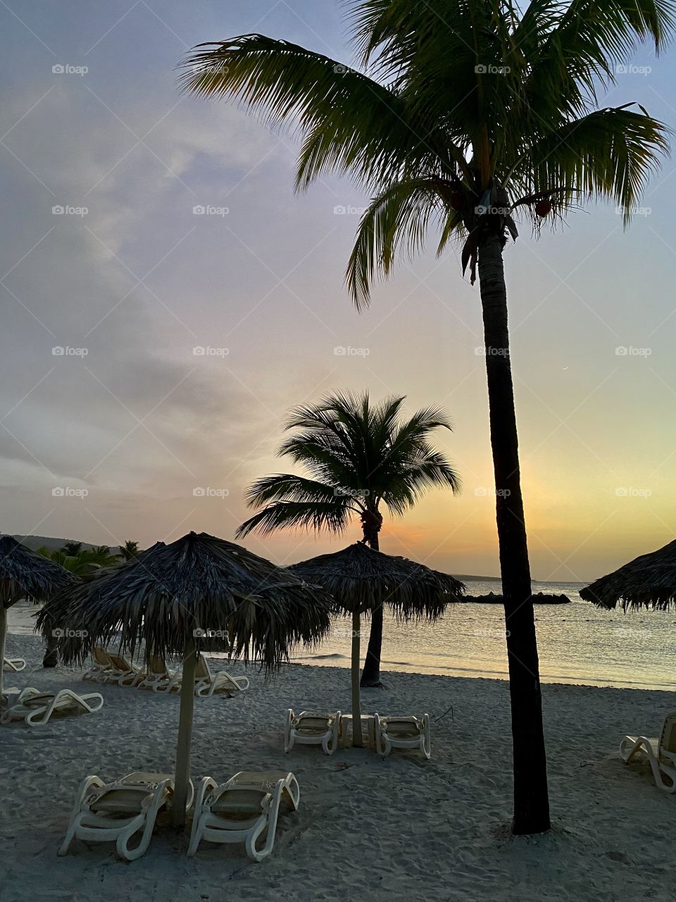 Beautiful sunset by a beach in the Bahia Principe Grand Jamaica hotel area with chaise lounges in front of it