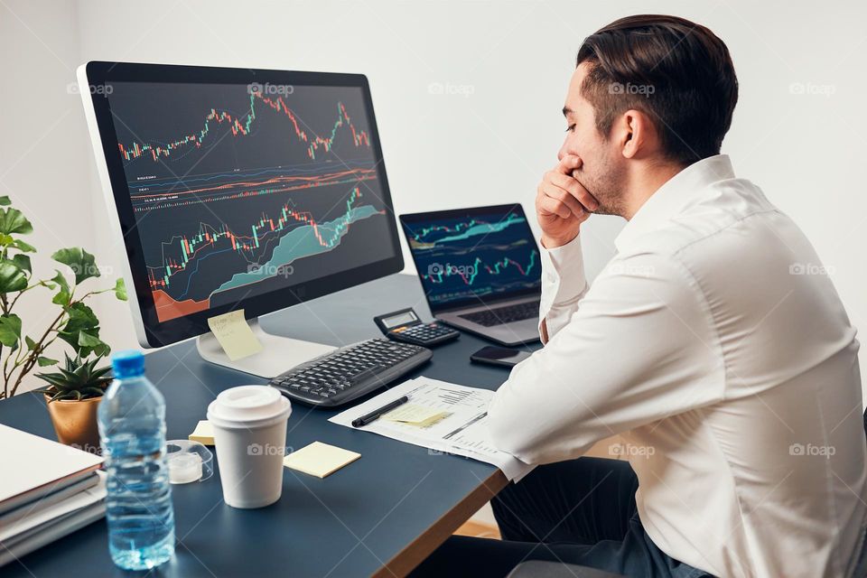 Worried businessman looking at charts stressed by news from stock market. Investor lost money online. Man analyses loss and profit. Businessman investing stocks online. Man working with stock chart data. Business investing trouble concept