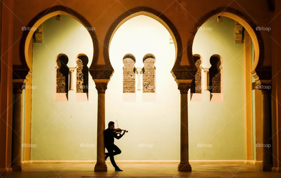 violinist silhouette under arches