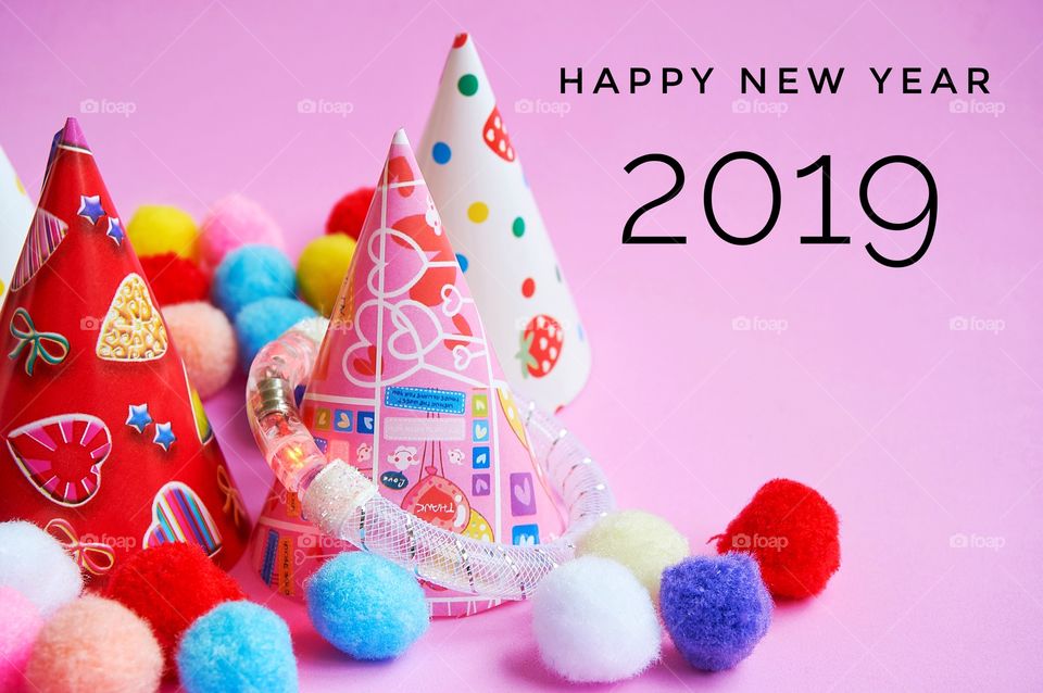 Happy new year 2019 with balls and party hats on pink background 