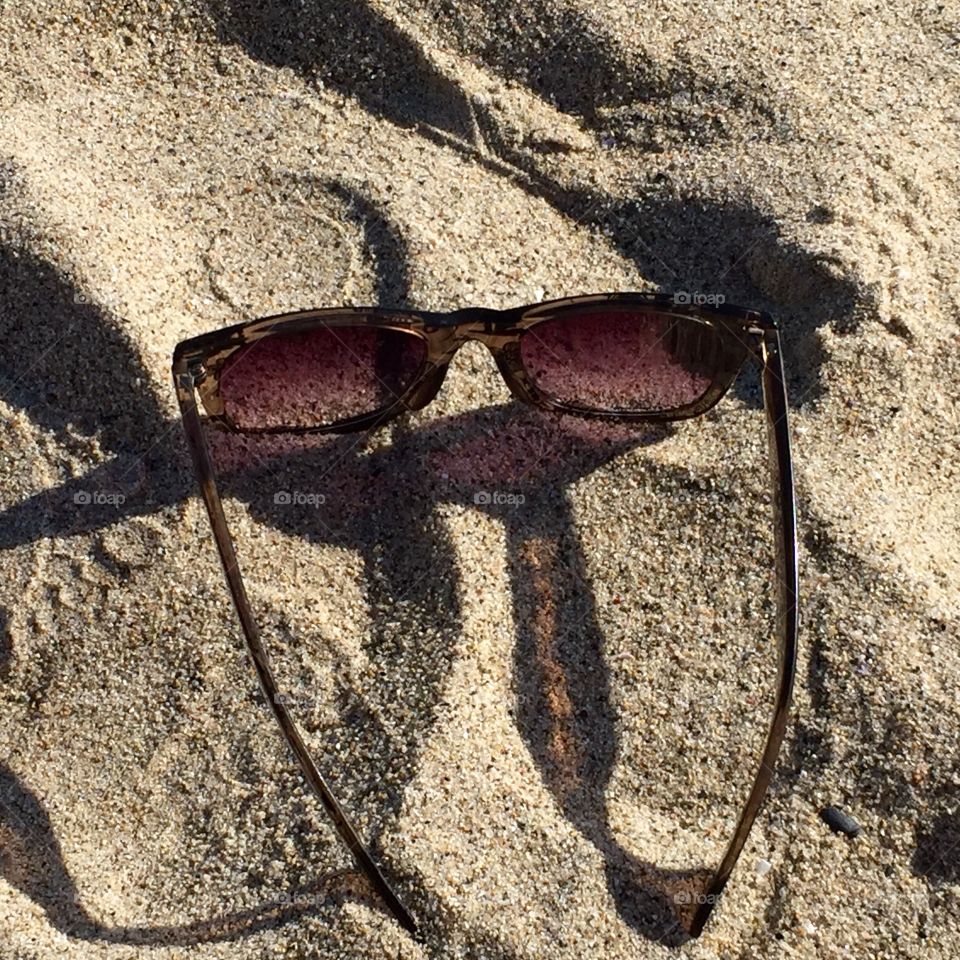 Elevated view of sunglasses on sand