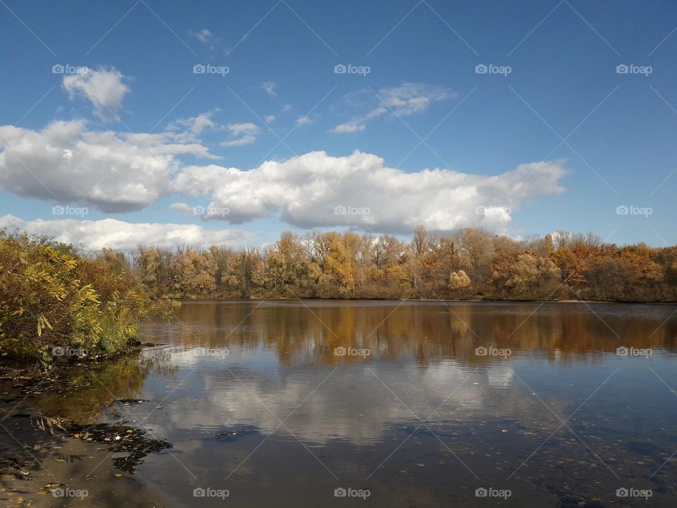 Autumn landscape with reflection of clouds in the river