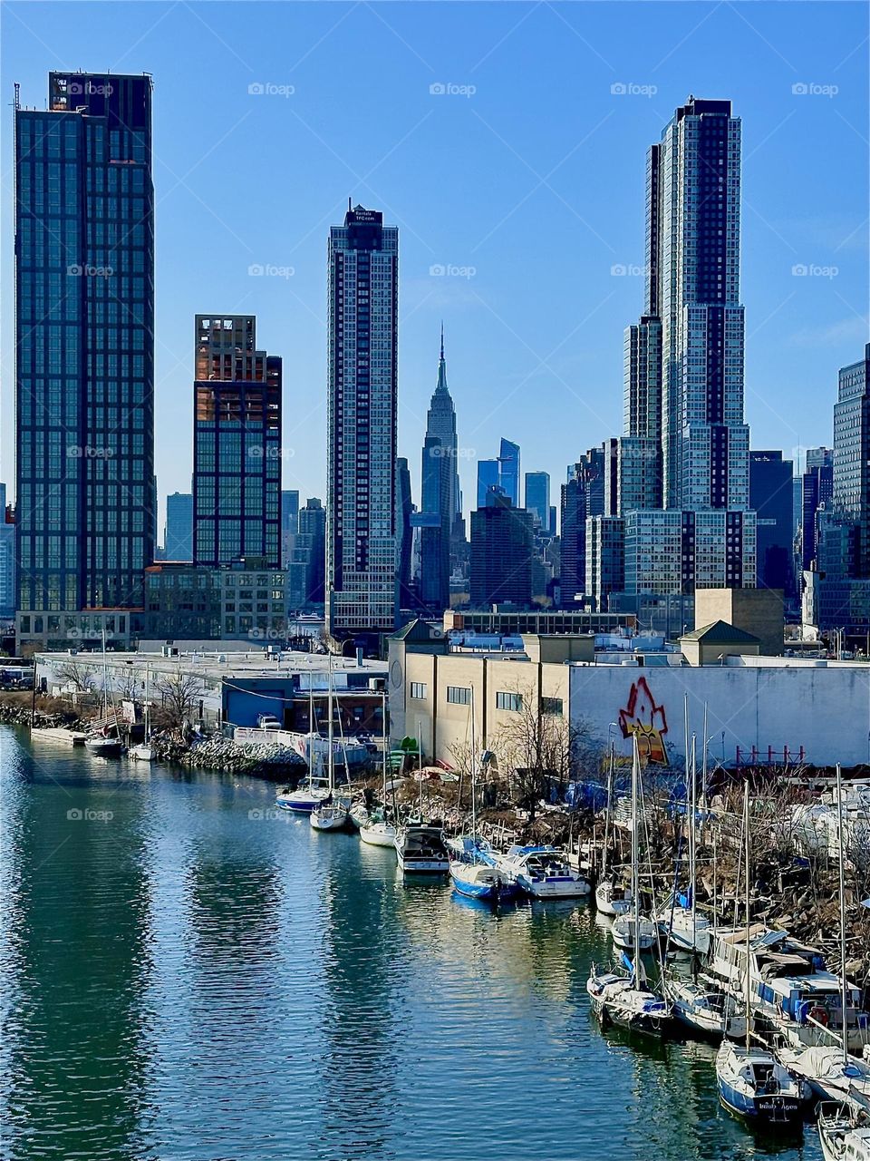 This is the gorgeous view of „Newtown Creek“ from the „Pulaski Bridge“ that connects „Greenpoint“, Brooklyn to LIC, Queens. Straight ahead we see LIC and in the further distance „Manhattan“ incl. the „Empire State Bldg“. 2024. Hypnotic Productions