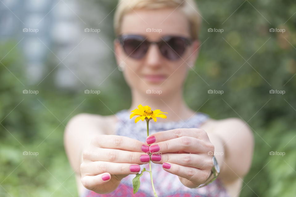 Woman gifting flower, hands in focus, face of woman out of focus