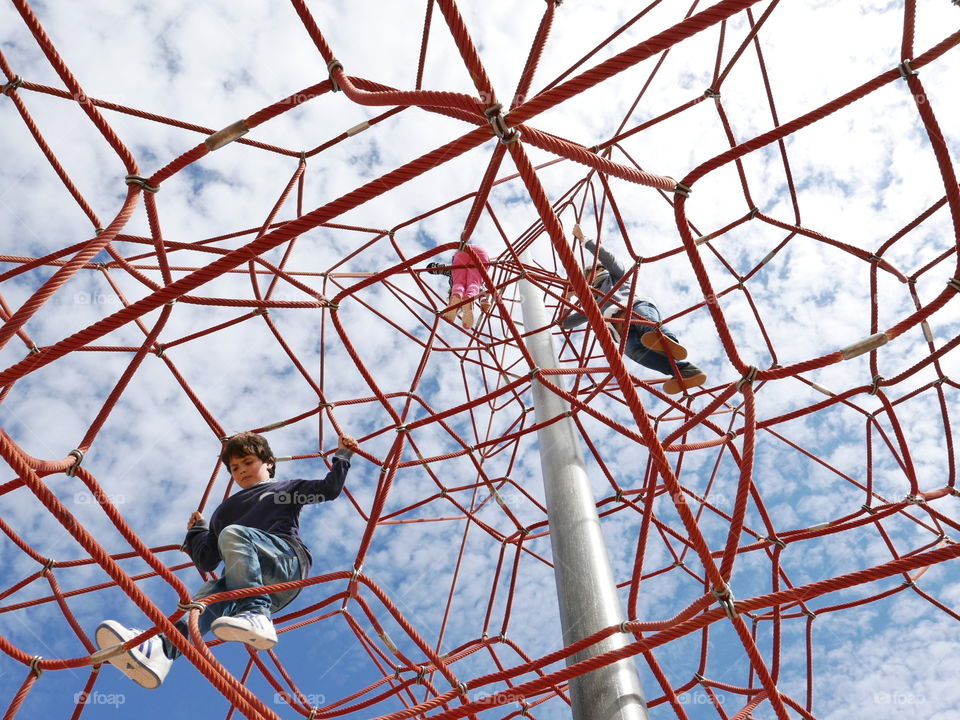 Low angle vie of children playing on jungle gym ropes