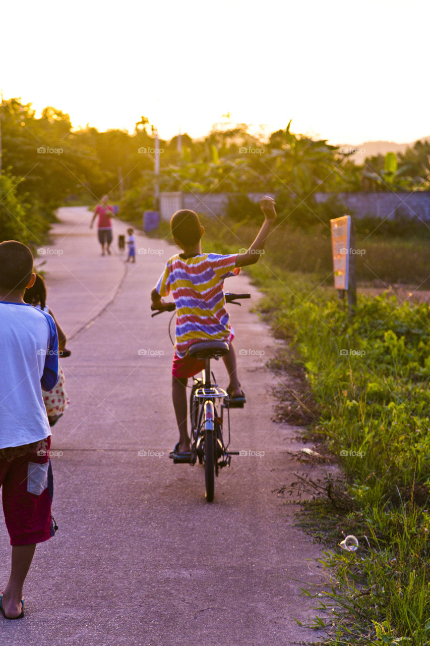 Friends. Asian kid enjoying outdoor activities, riding bicycle