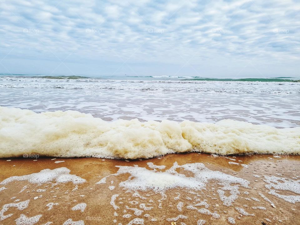 foamy wave of the sea crashes on the shoreline
