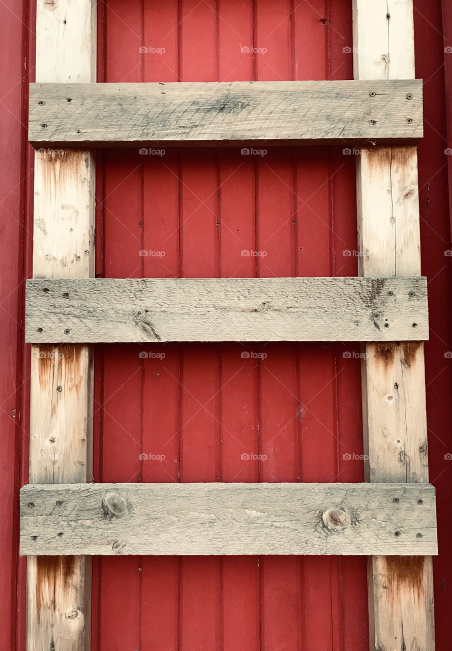Old wooden ladder against a red barn