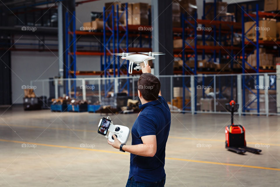 Men from behind using drone on warehouse 