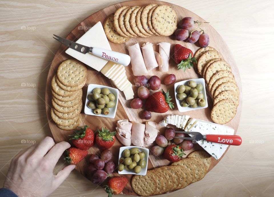 Healthy food, vegetables fruit and cheese charcuterie wheel, hand in frame