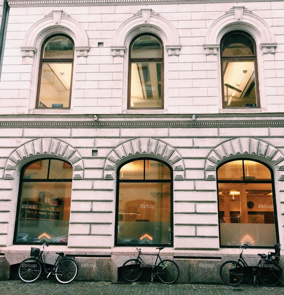 Bikes perfectly lined up against a historic building. 