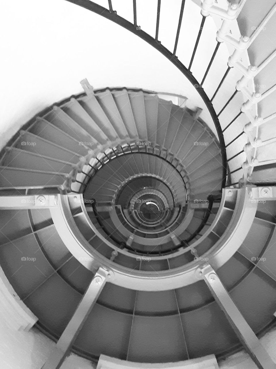 A black and white photo of the steep spiral staircase of the Ponce Inlet Lighthouse.