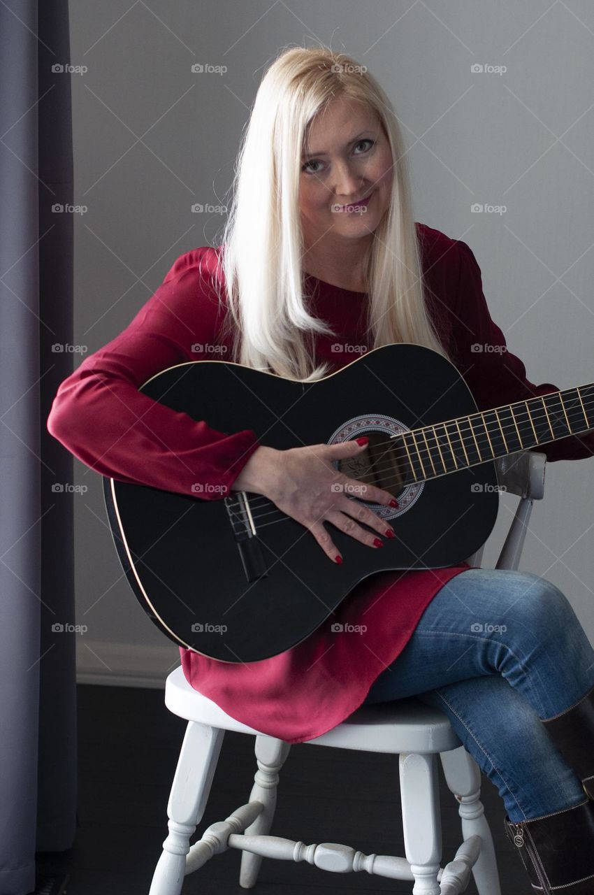 blonde girl in a red dress plays the black guitar