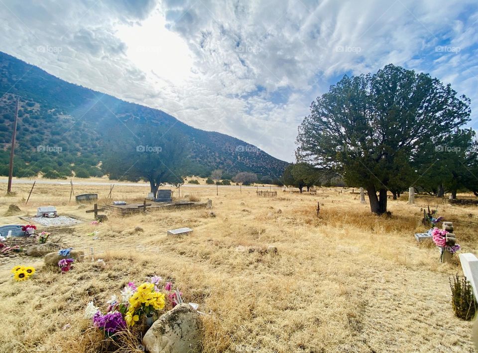 Sunbeam thru cloudy blue skies over a New Mexico Mountain graveyard