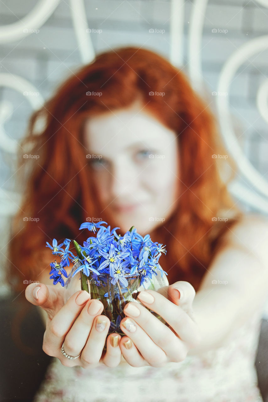 Redhead woman with freckles holding a beautiful purple  snowdrops in her hands close up. Gift ideas for holiday.