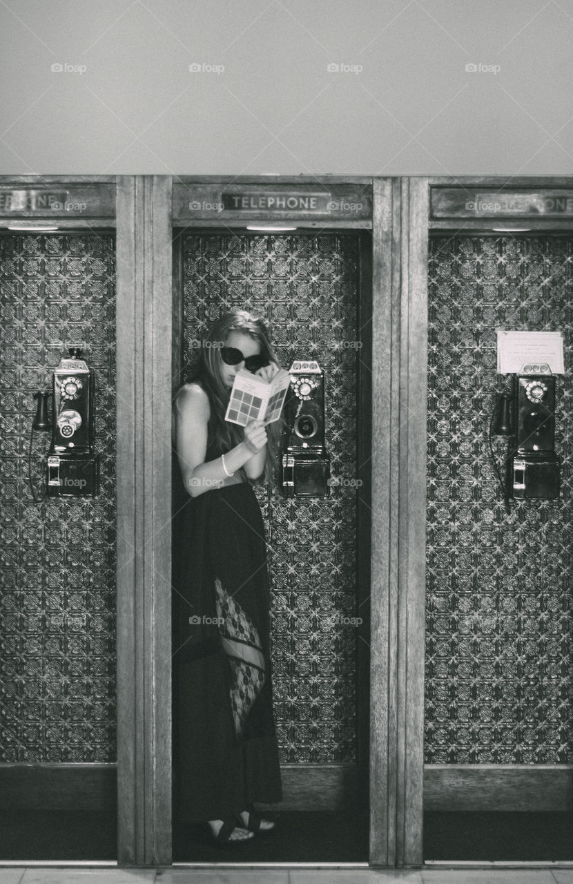 Woman standing inside telephone booth