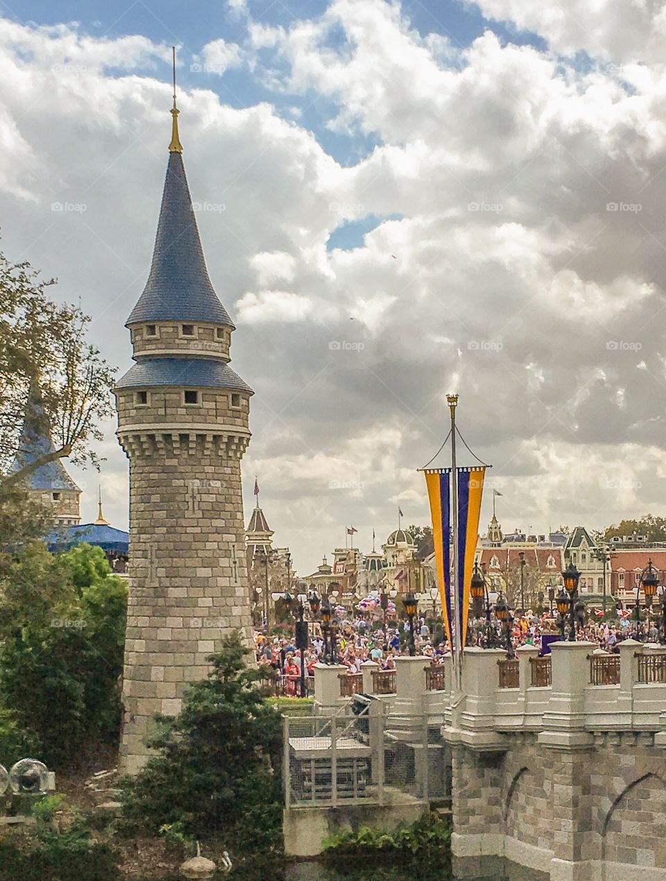 A tower of Cinderella castle looking out onto the courtyard in front.  People are gathered for the next show. 