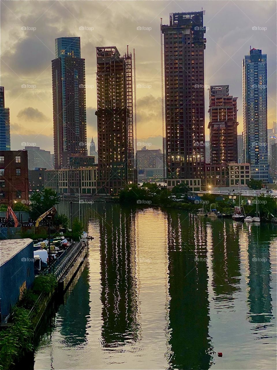 This is „Newtown Creek“ by the „Pulaski Bridge“ in LIC, Queens at twilight time. The last golden rays of the setting sun can be seen through the LIC skyscrapers including those currently under construction. 2023. Hypnotic Productions