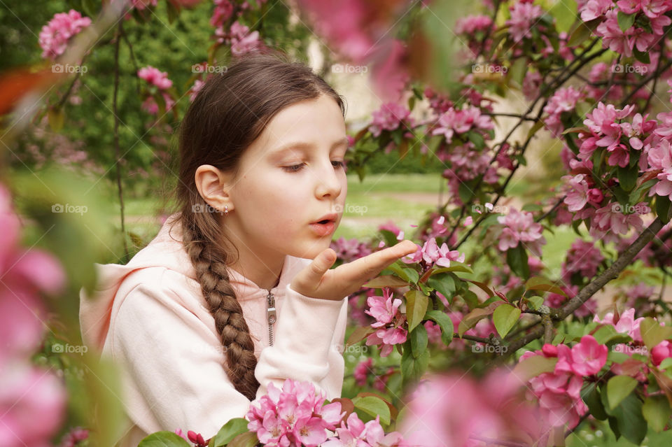 Girl blows pink flower petals from her palm