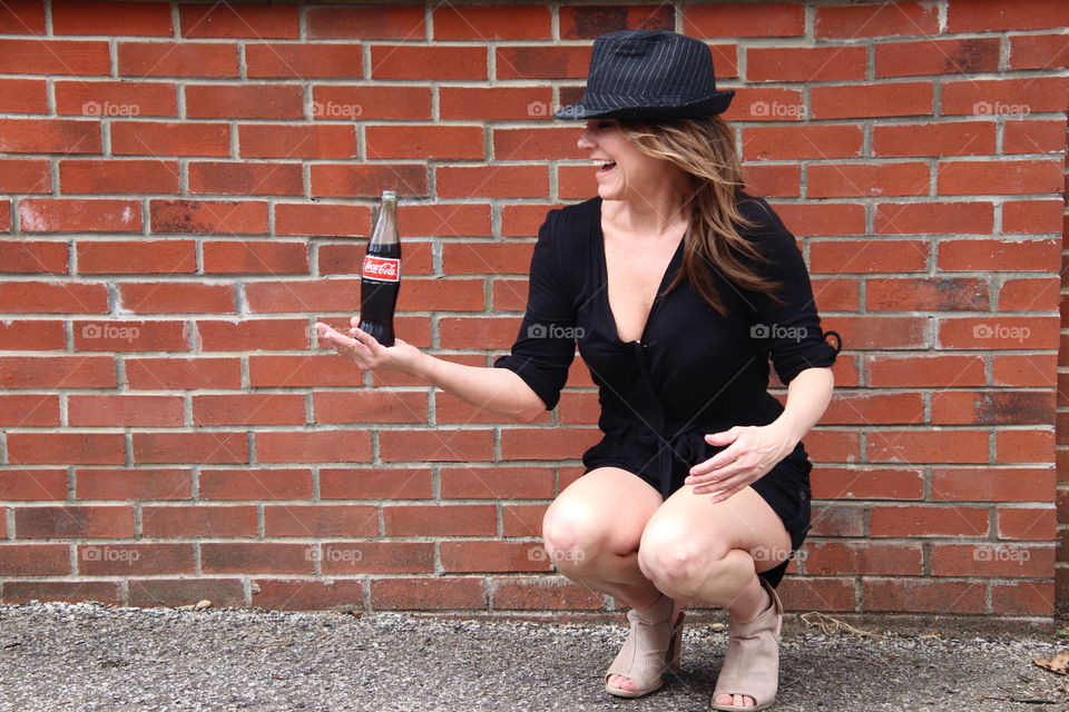 Female in front of brick wall holding Coca Cola 