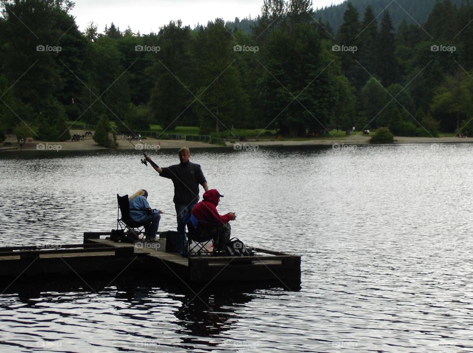 Several people fishing on an Autumn’s day off the peaceful shores of Bunzten Lake outside Vancouver, British Columbia 