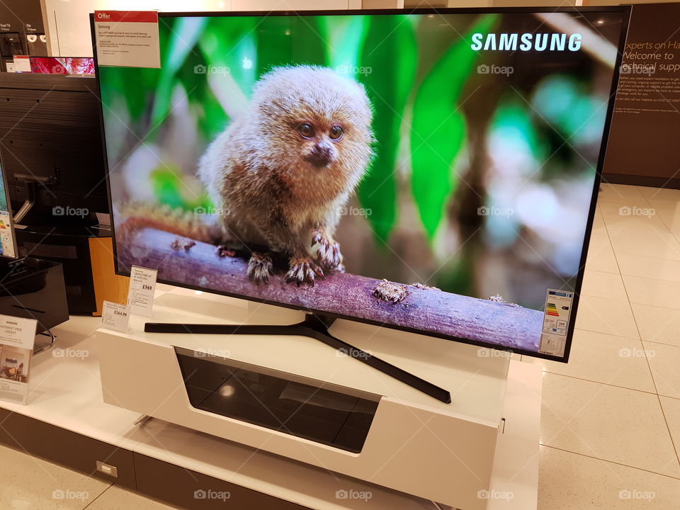 Samsung 65" 4K UHD television with black bezel on white TV stand
