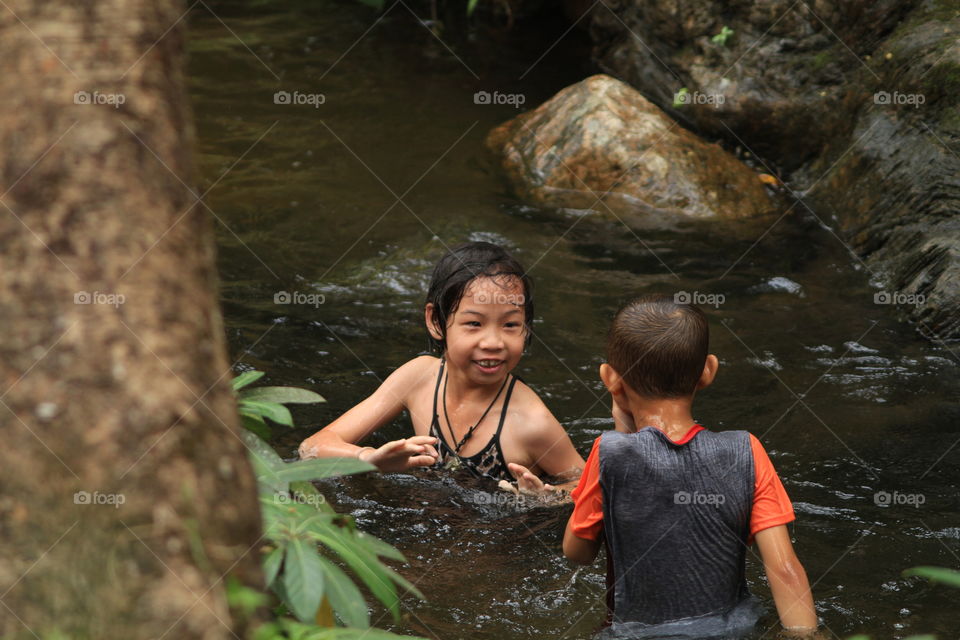 Girl and boy playing in water. Girl and boy playing in waterfall in spring. 
