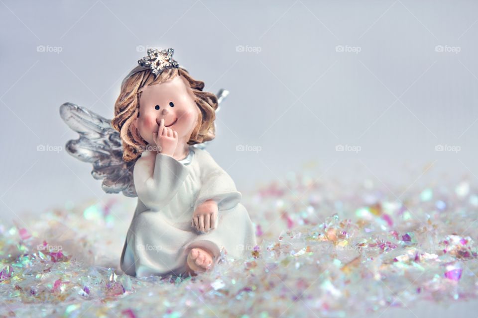 A toy angel sits on a background of artificial snow.