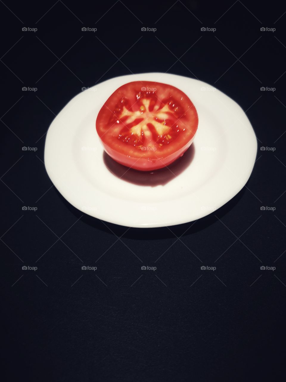 Red tomato on a white saucer