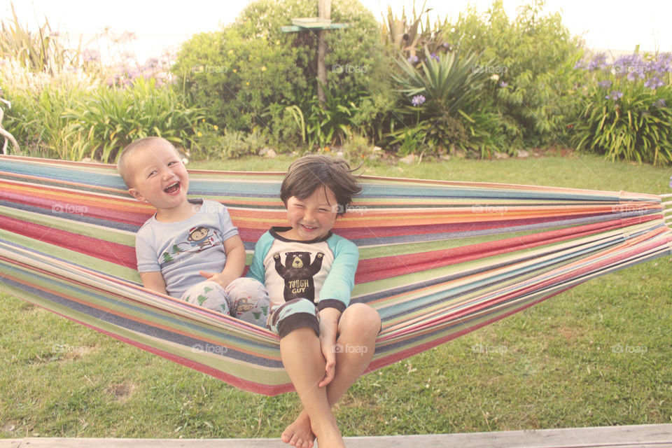 Brother and sister sitting on hammock