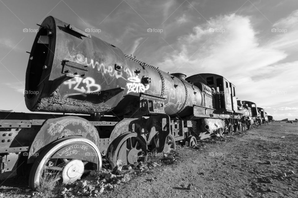 Abandoned train in desert. Abandoned old locomotive in desert. Black and white photo. Yuni, Bolivia. Train partly inside ground