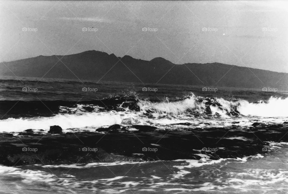 Waves crash on the shining shore of Hawaii. 