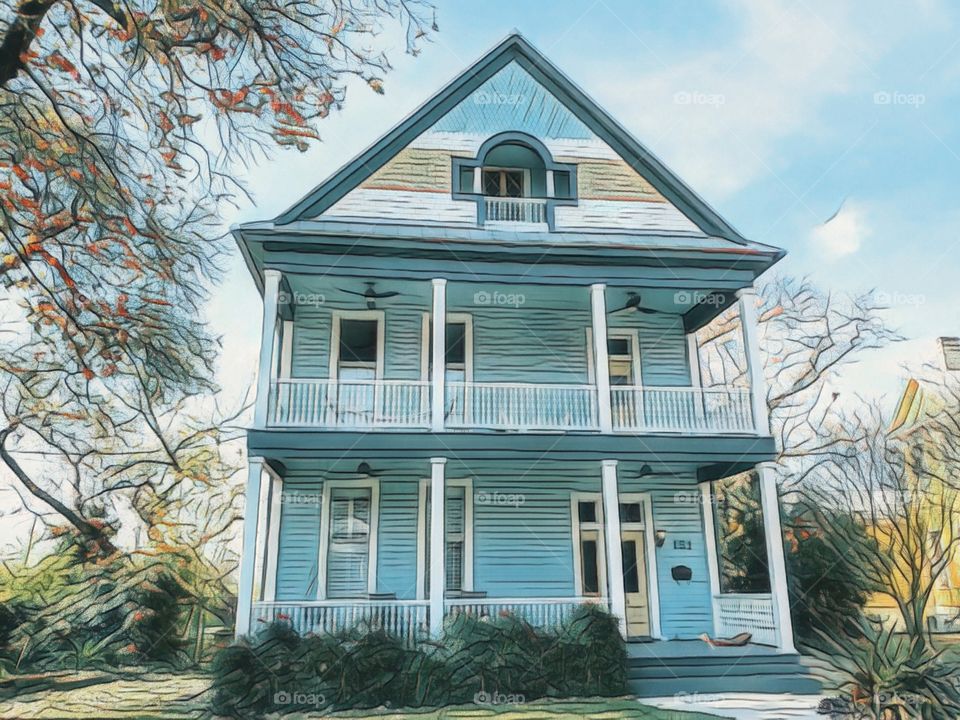 Bright light blue two story historic home with a second floor balcony and attic.