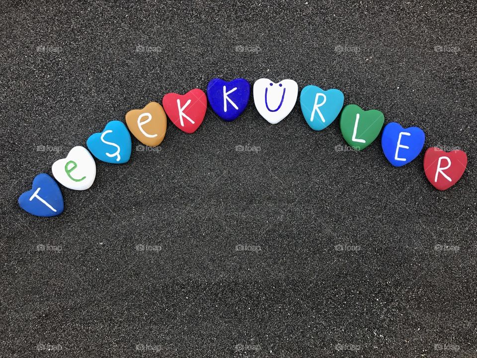 Teşekkürler, turkish thank you with colored heart stones over black vulcanic sand