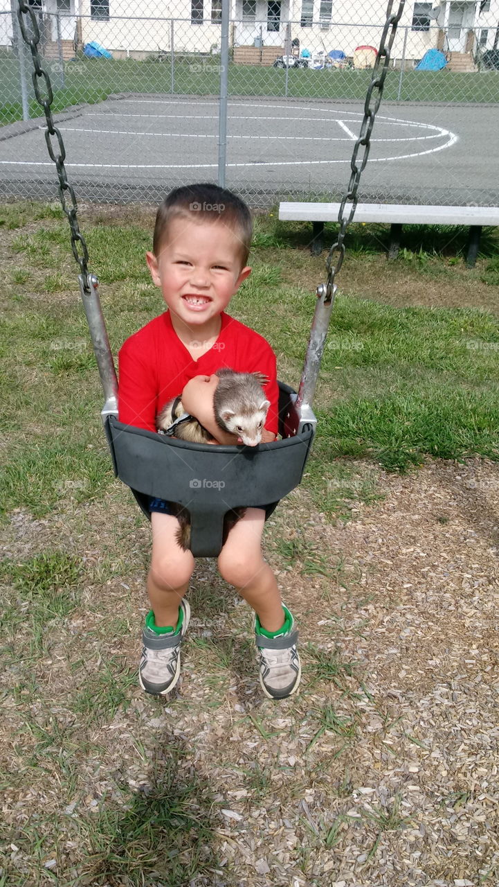 five year old son with our ferret at the play ground on the swings