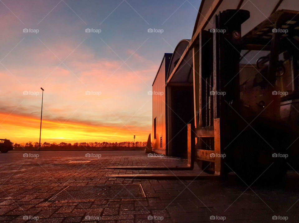 a forklift truck in its hangar during a beautiful sunset