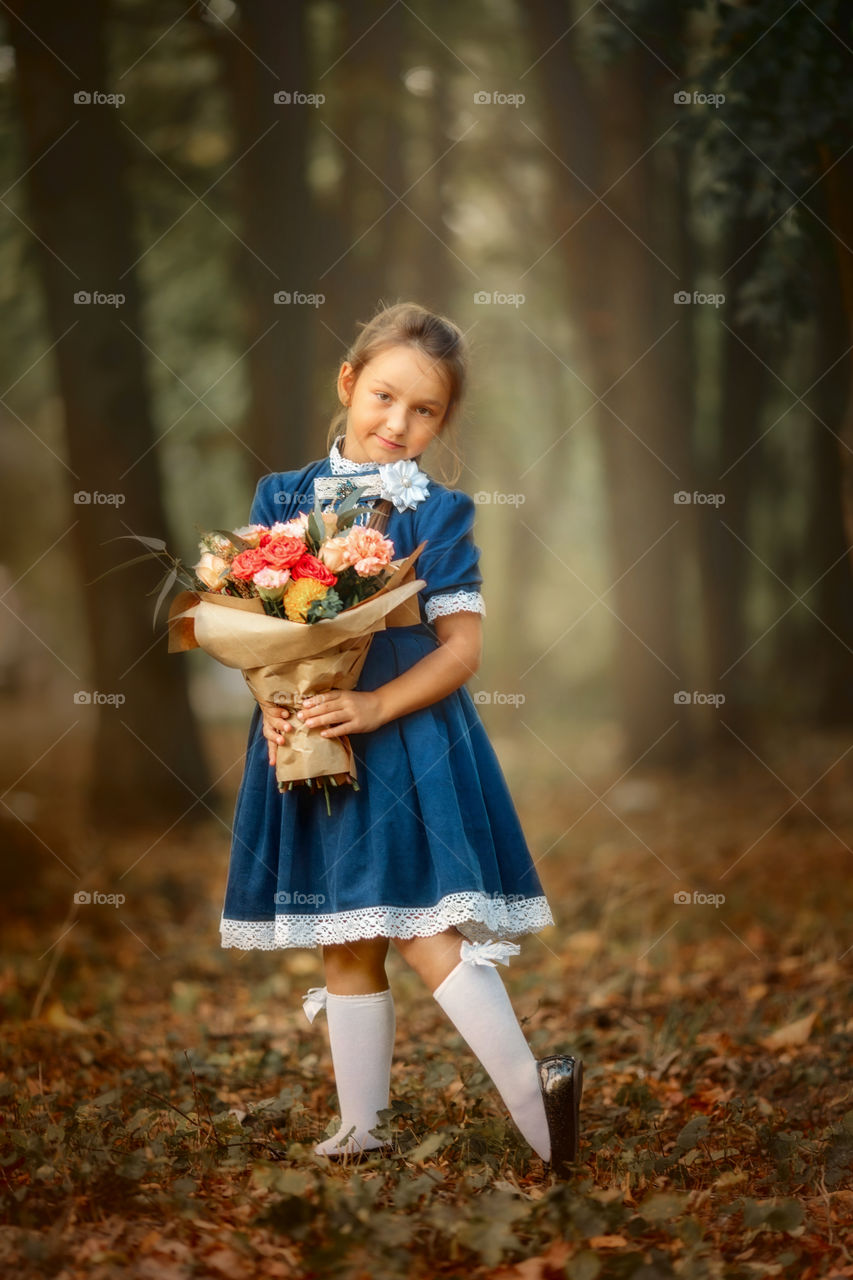 Little schoolgirl with a bouquet at a park 