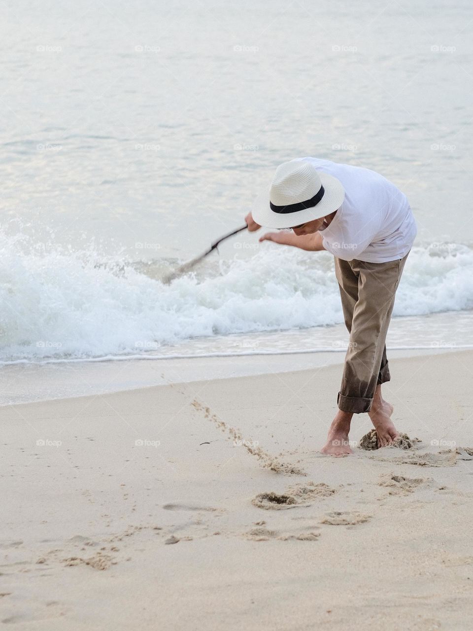 A teenager playing stick on the beach on his morning beach walk