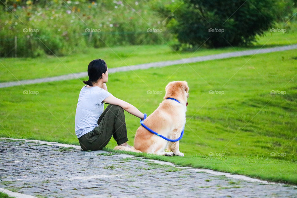 A Women Sitting with Her Dog in A park.