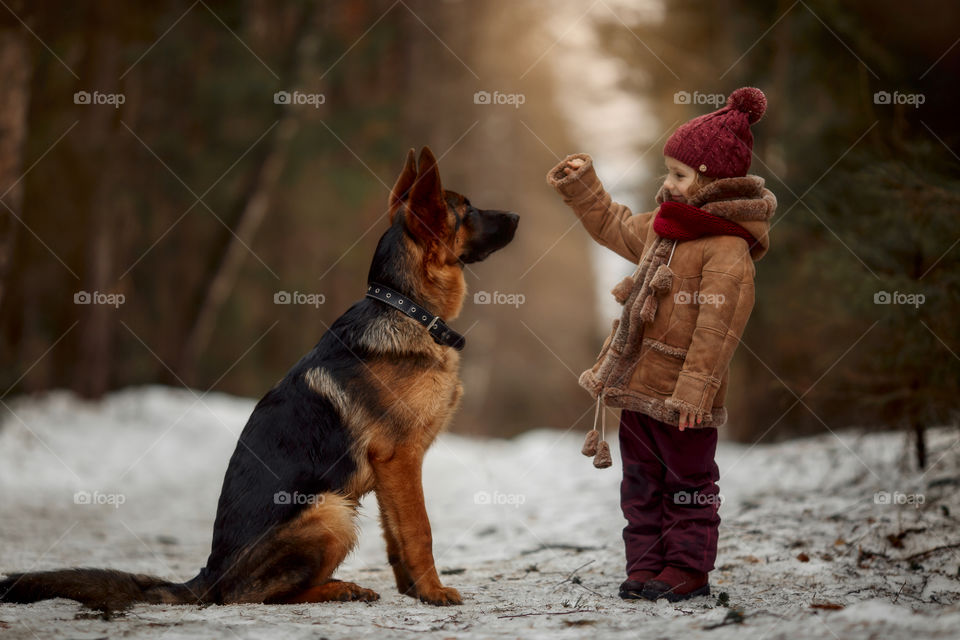 Little girl with German shepherd 6-th months puppy at early spring forest