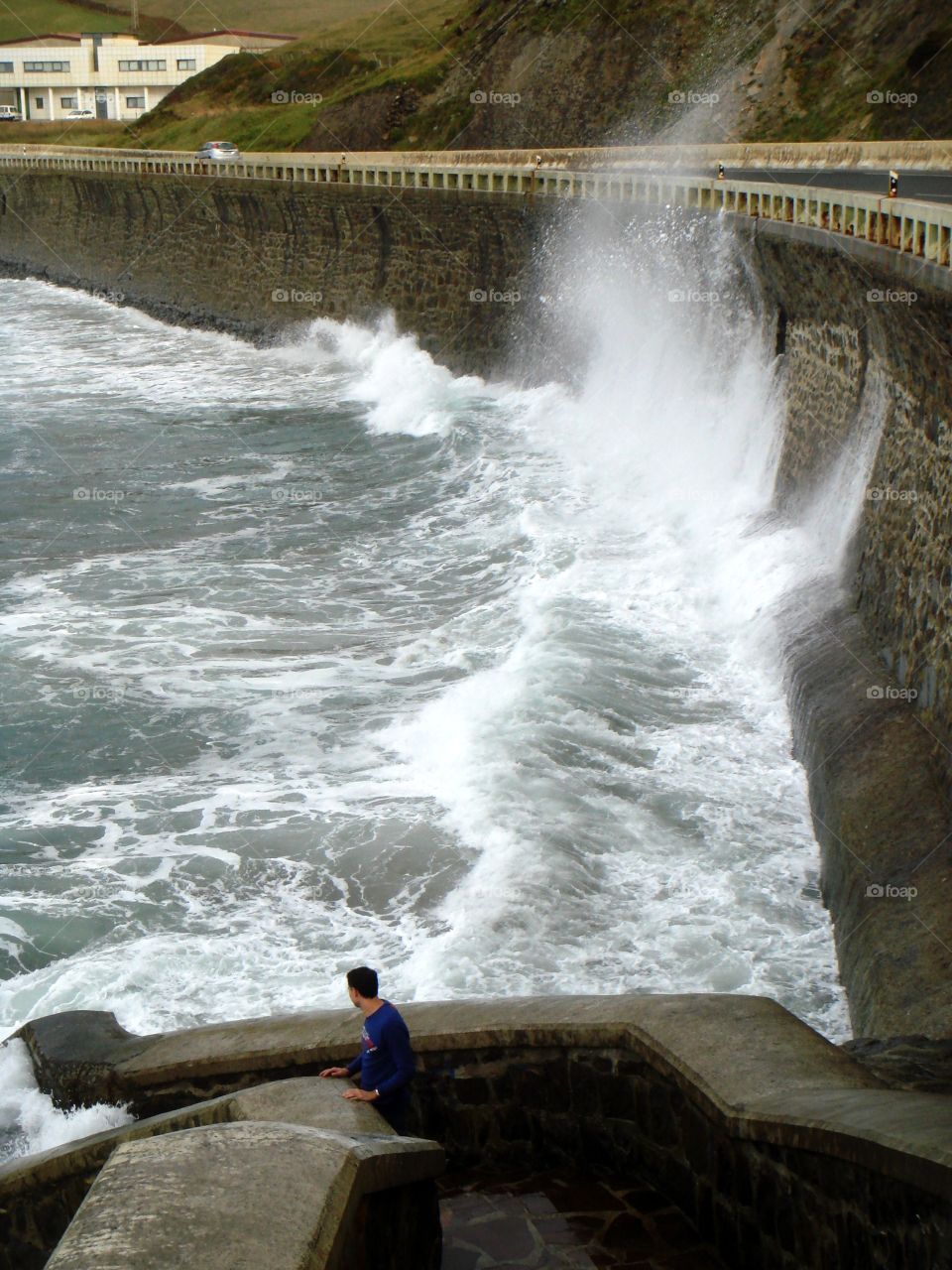 a man watching the waves against a wall
