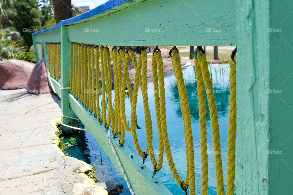 Colorful wooden fence with roping along a pond