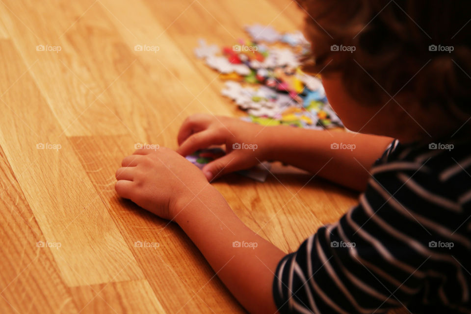 Kid putting together puzzles on the floor