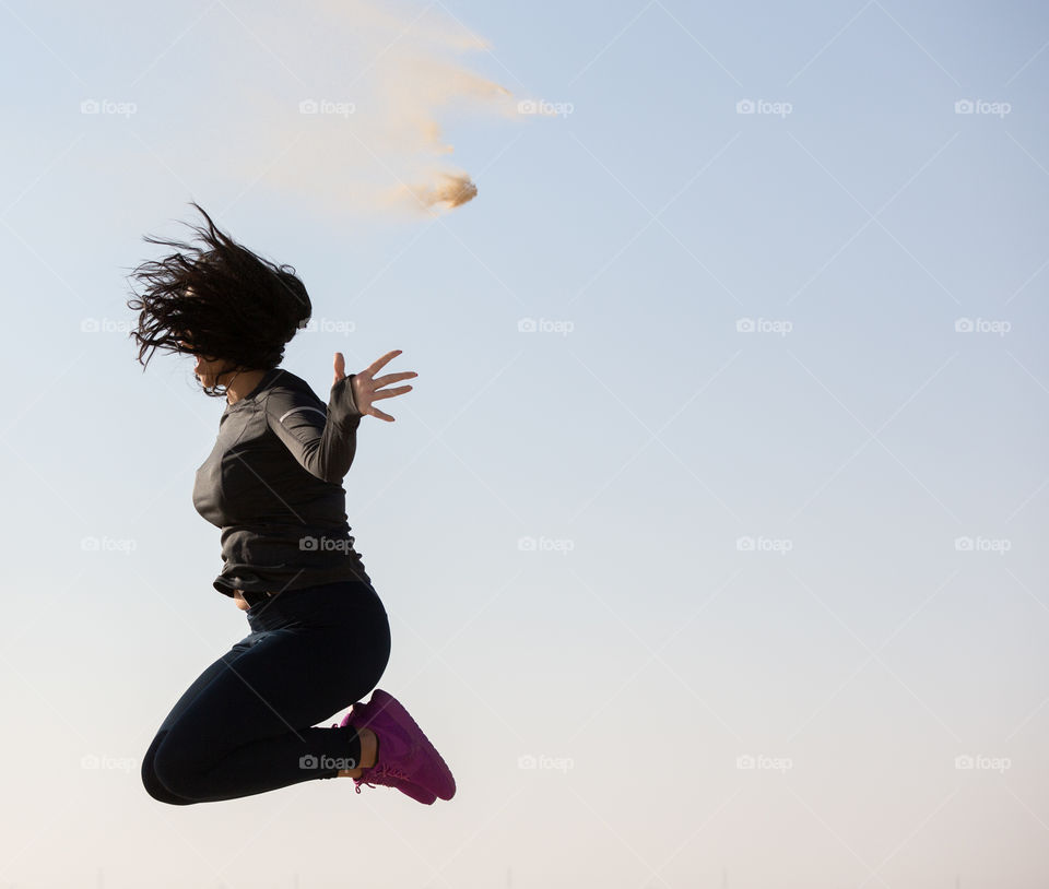 Woman Jumping with a joy. Desert Sand particles are shown in the air. 