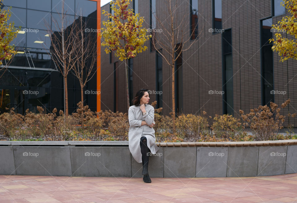 young, beautiful girl sits alone, social distance, for one person in the city