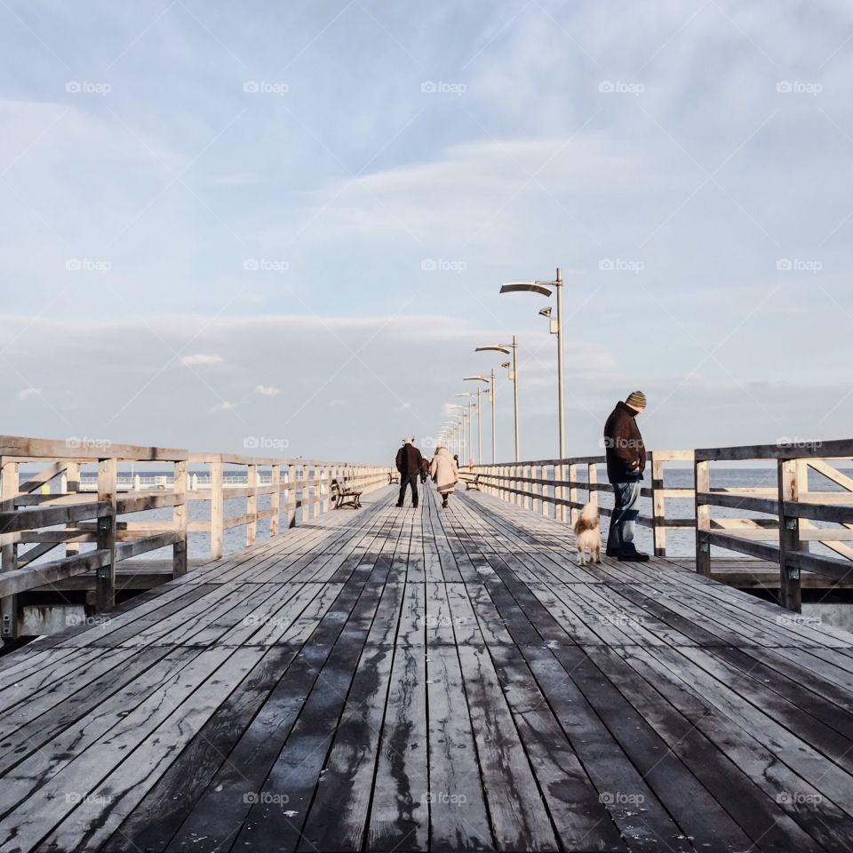 Tourists walking on wooden pier at sea